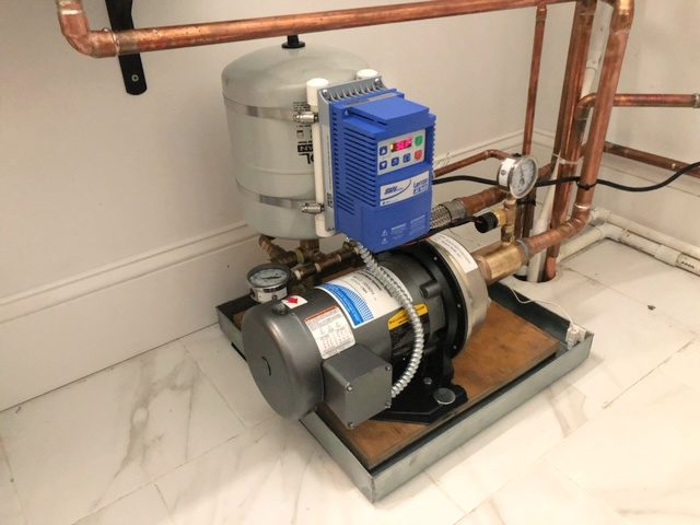 A booster pump and tank in the corner of a room.