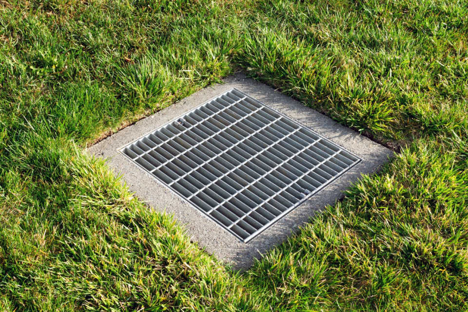 Metal grate in the middle of grass.